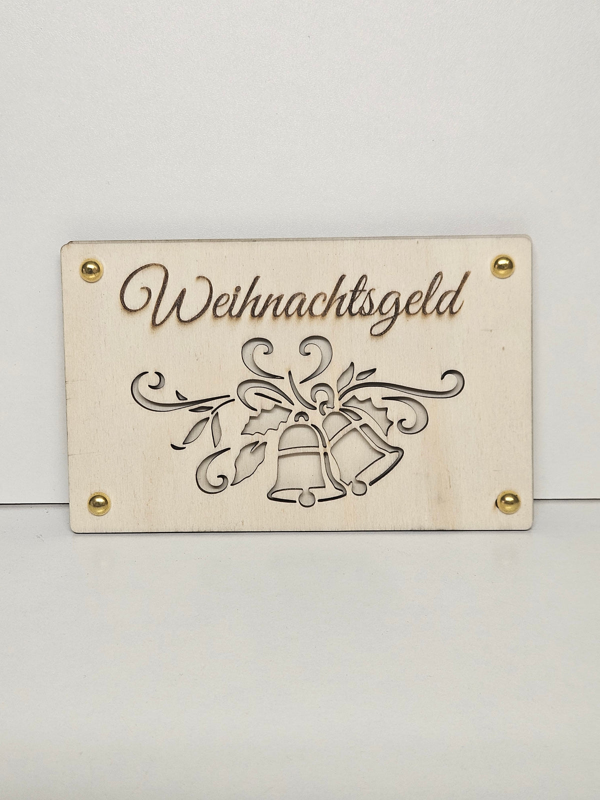 Rechteckiges Geldgeschenk aus hellem Holz mit Schriftzug Weihnachtsgeld, Glockenmotiv und vier goldfarbenen Eckdetails