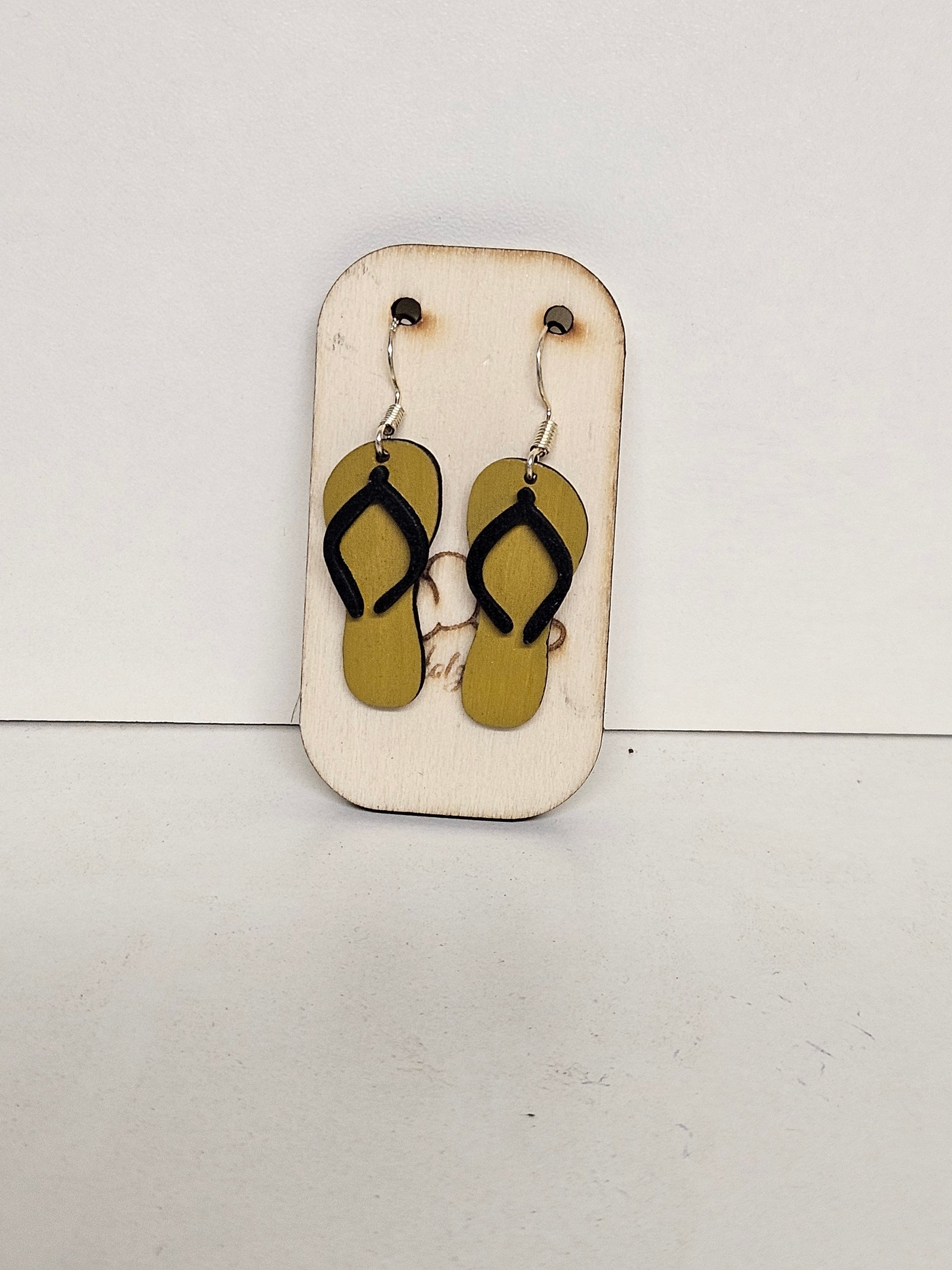 Handgemachte Holz-Ohrringe Flip-Flop Oliv-Khaki mit schwarzen Riemchen und 925 Silberhaken auf Holzdisplay