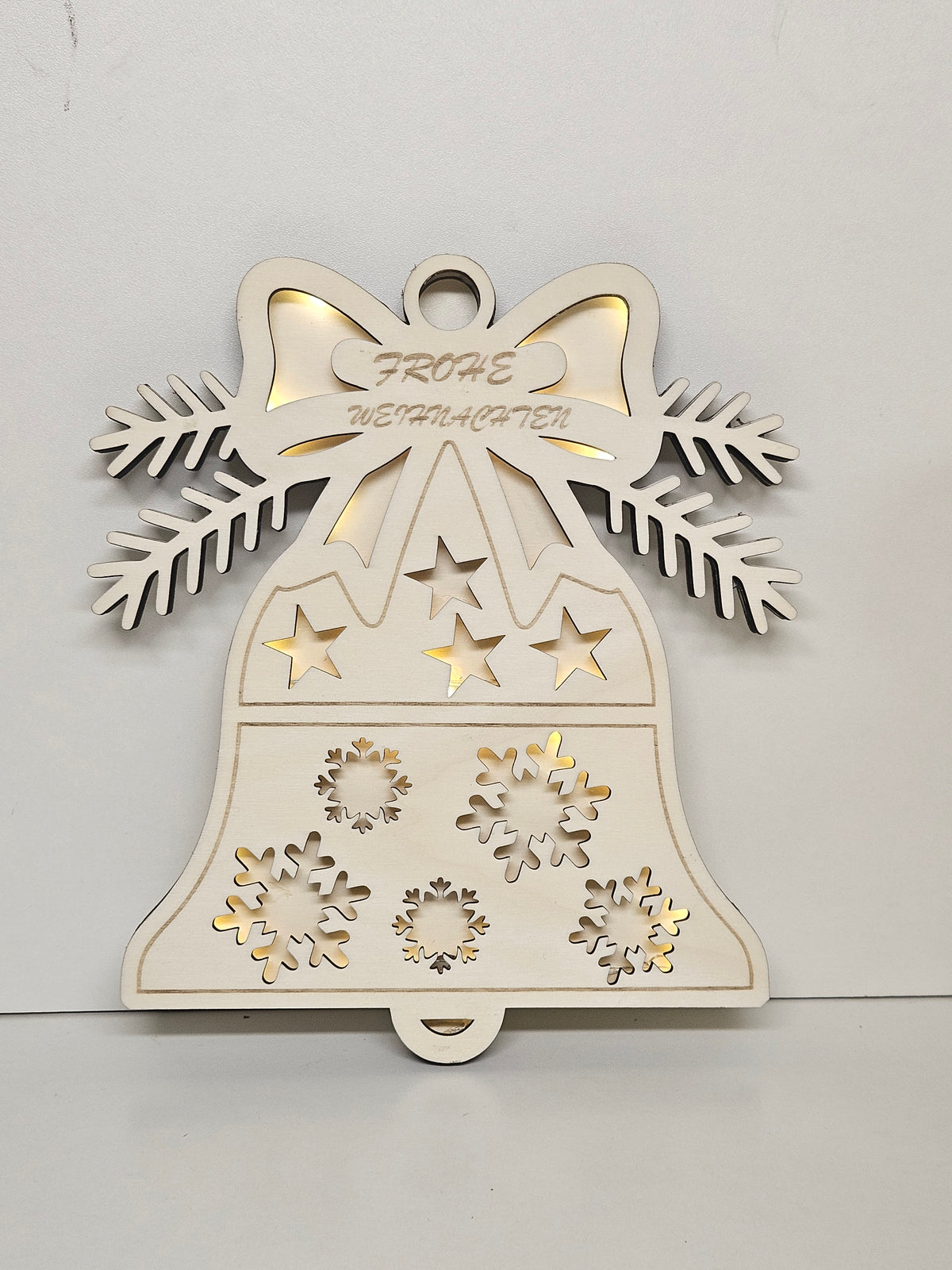 Leuchtende Weihnachtsglocke mit Schleife, Schneeflocken und Sternen