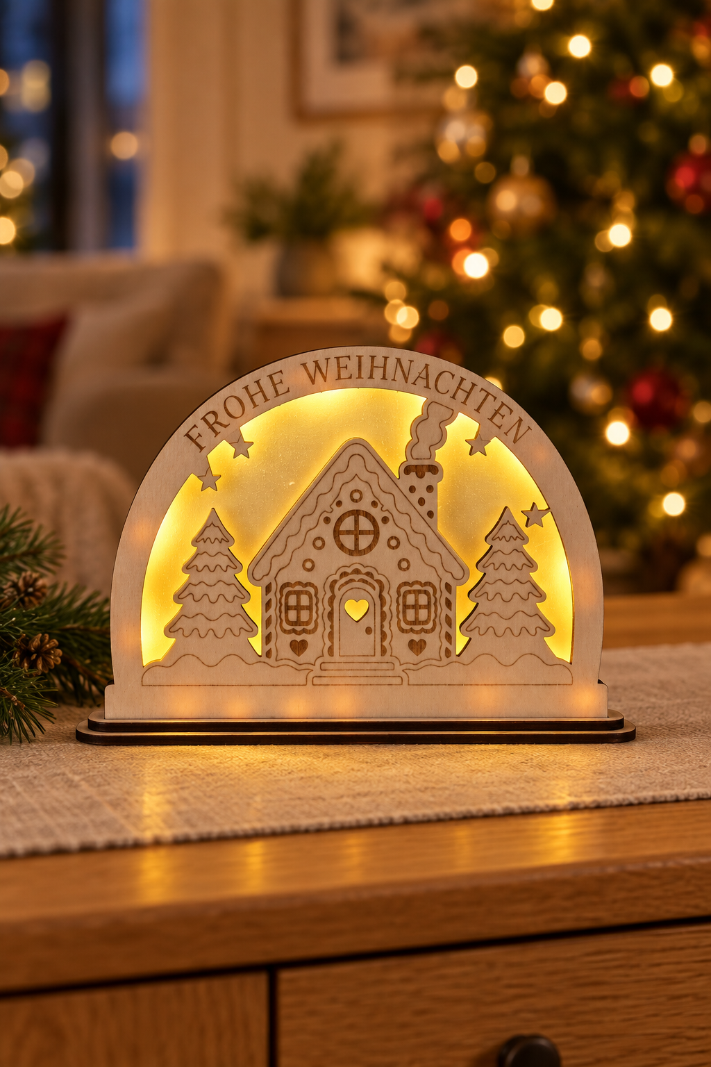 Weihnachtslampe mit Lebkuchenhaus auf einer Kommode im weihnachtlichen Wohnzimmer